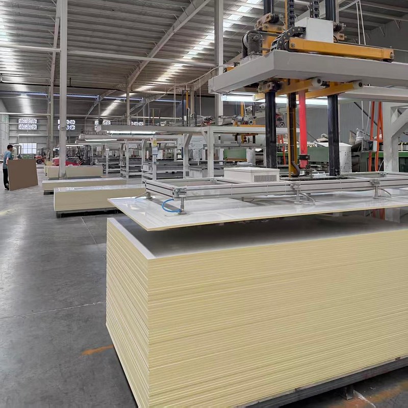 PVC wall panel production at the VIGOU factory — carbon crystal core boards stacked under the laminating press